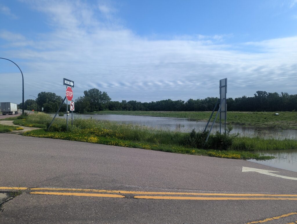 A road with a sign and a lake.