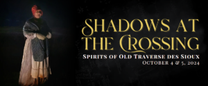 A person dressed in historical attire stands in the dark with a faint light illuminating them. They wear a white dress, a shawl, and a red bonnet. The text reads, "Shadows at the Crossing: Spirits of Old Traverse des Sioux, October 4 & 5, 2024.